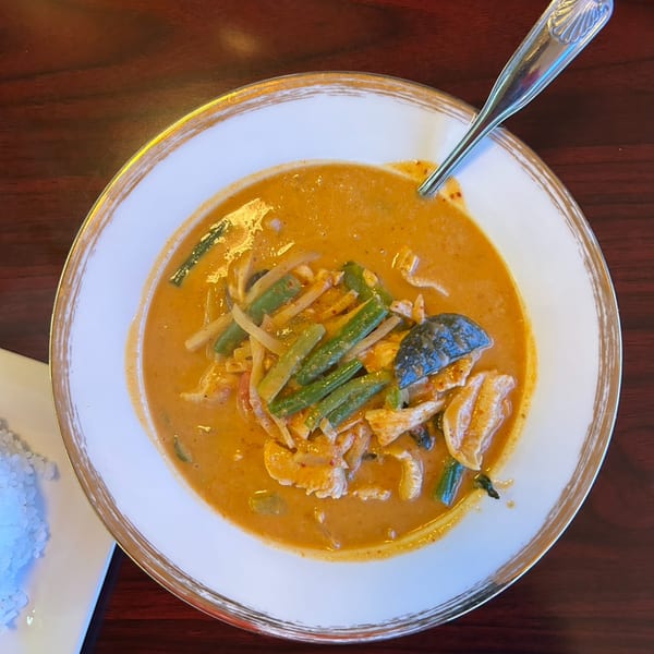 Overhead view of a bowl of Thai red curry with chicken, green beans, and bamboo shoots.